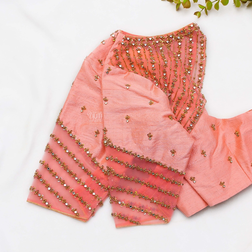 A pink blouse with gold beads and a plant